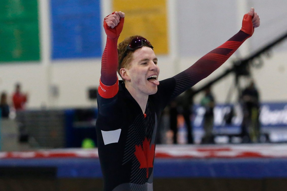 Speed skater holds his arms up in the air in celebration
