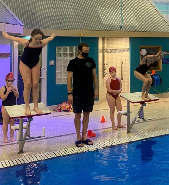 Coach with swimmers on start blocks