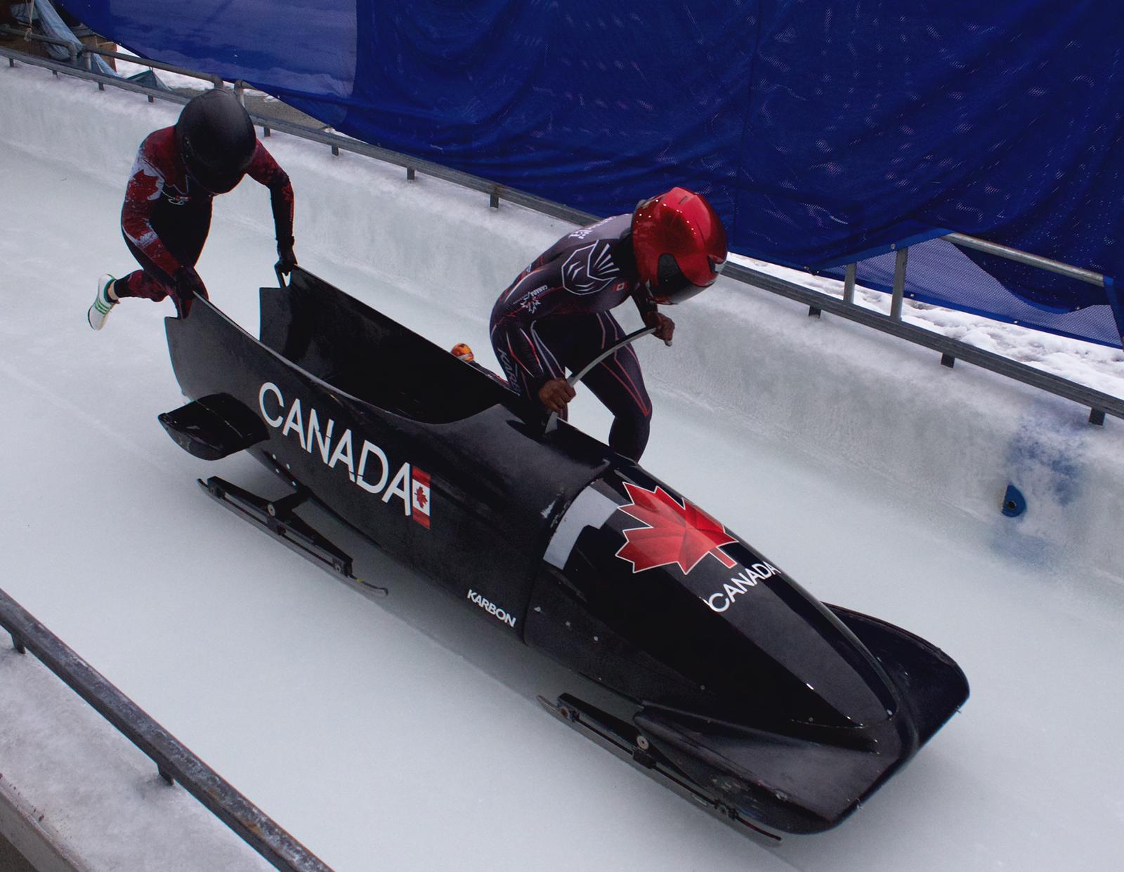 Two bobsledders push a sled at the start of a run 