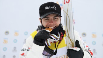 Mikael Kingsbury takes a bite of his world championship gold medal that is shaped like a snowflake.