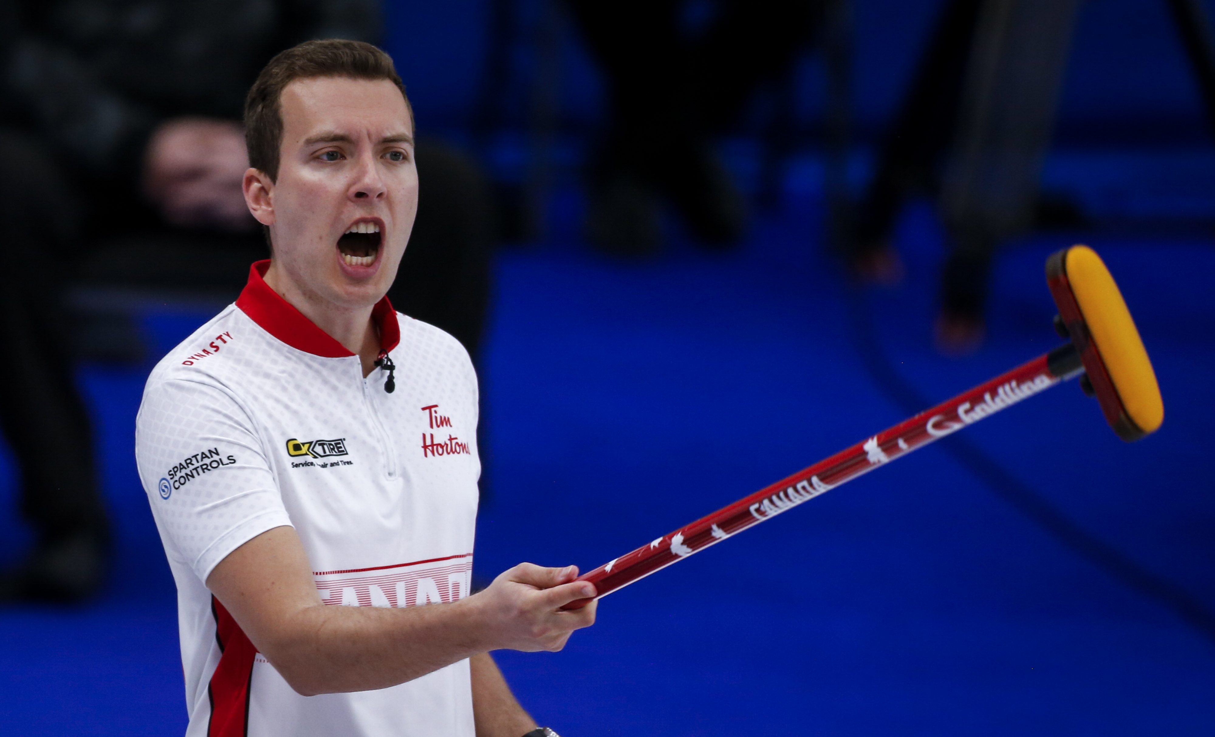 Curler holds his broom up while yelling