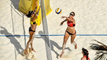 A high angle shot of Sarah Pavan (centre) sends the ball back to Talita Da Rocha during a beach volleyball game.