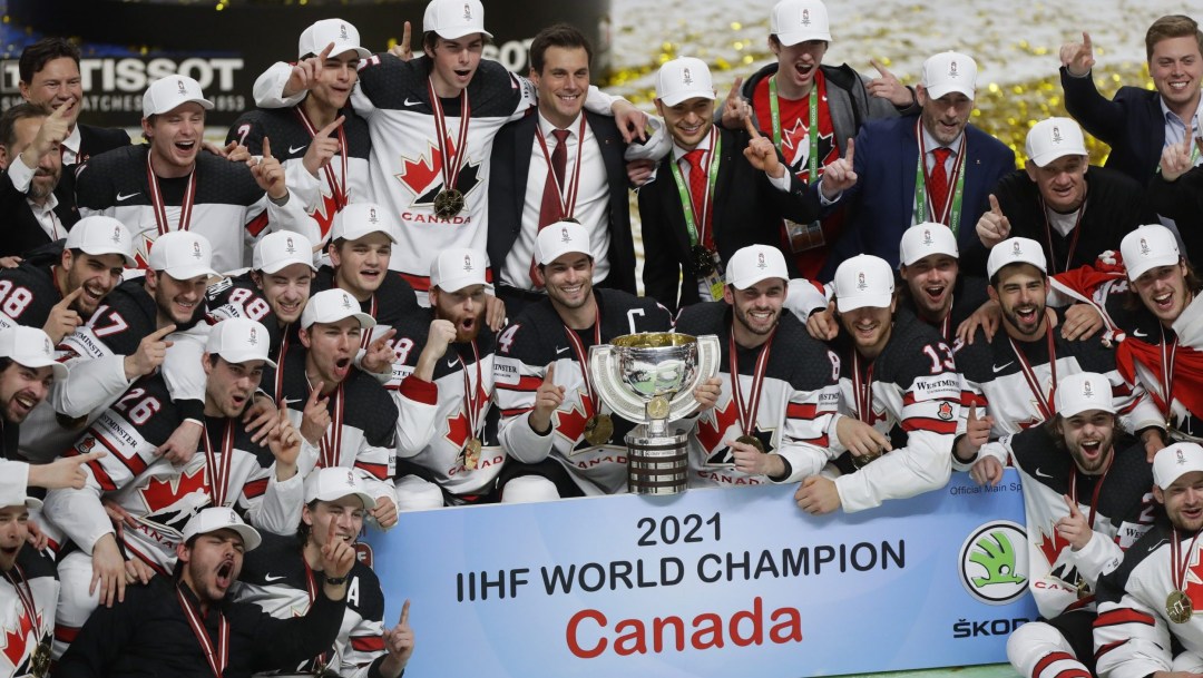 Team Canada hockey players sit together on ice with gold medals and trophy