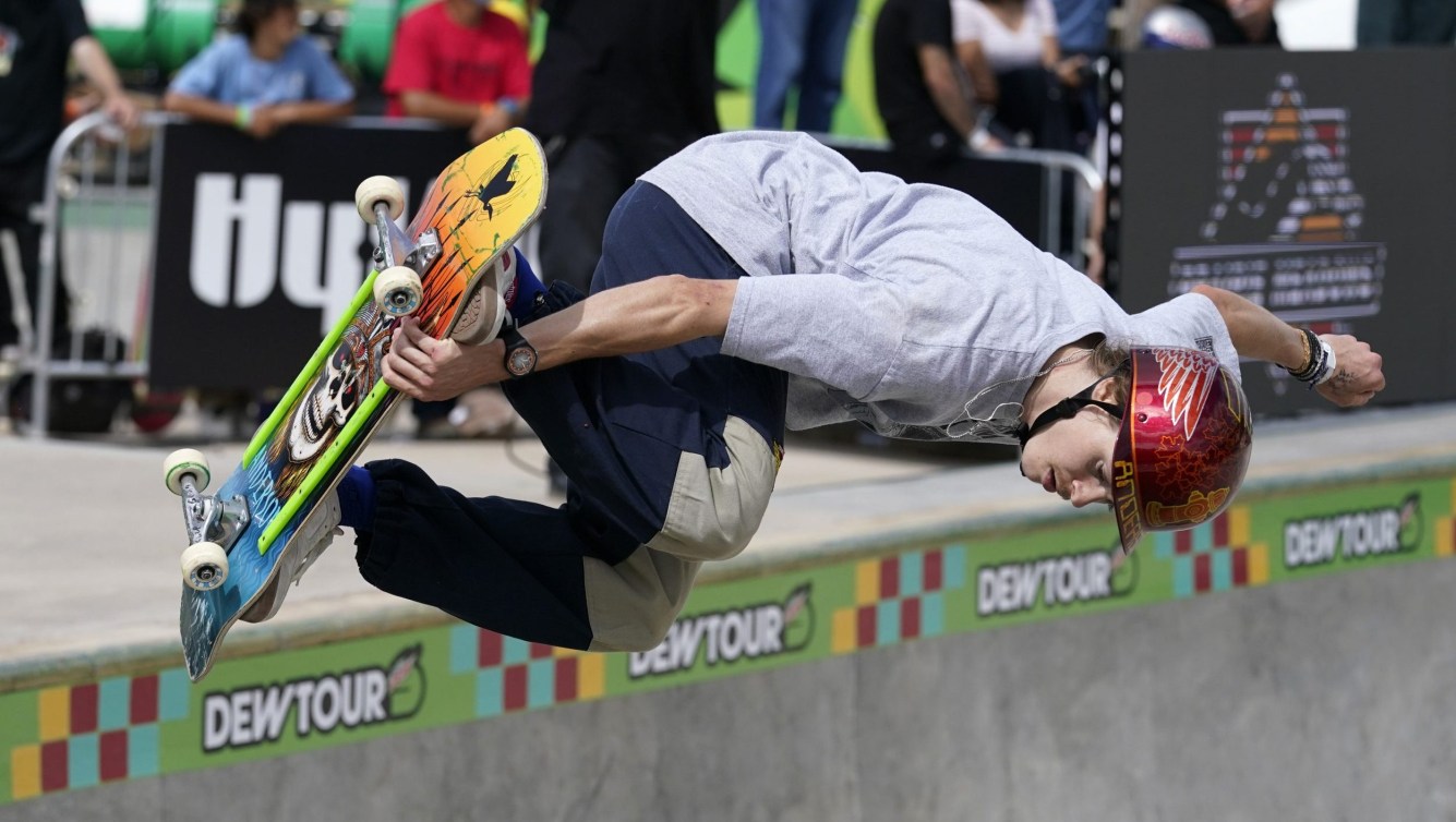 Andy Anderson grabs his skateboard on a trick