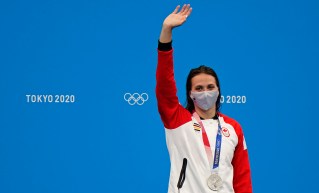 Kylie Masse in a Canada jacket, waving with her silver medal around her neck