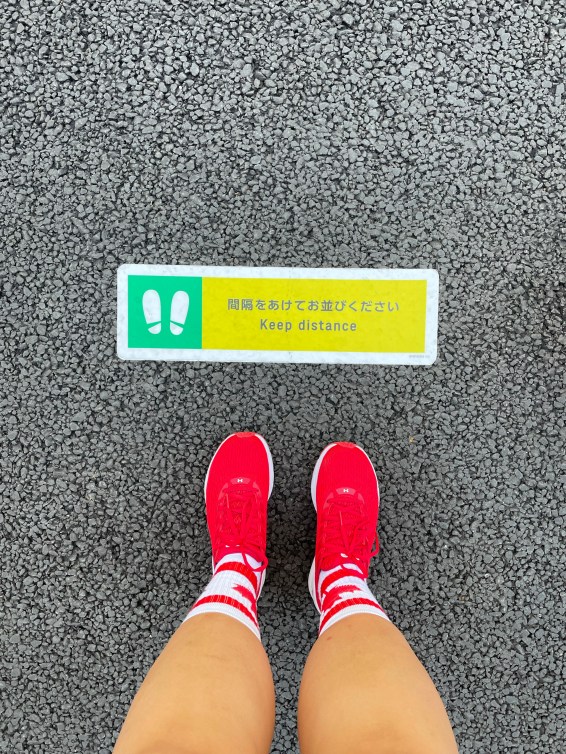 Red pair of sneakers standing on a social distance marker