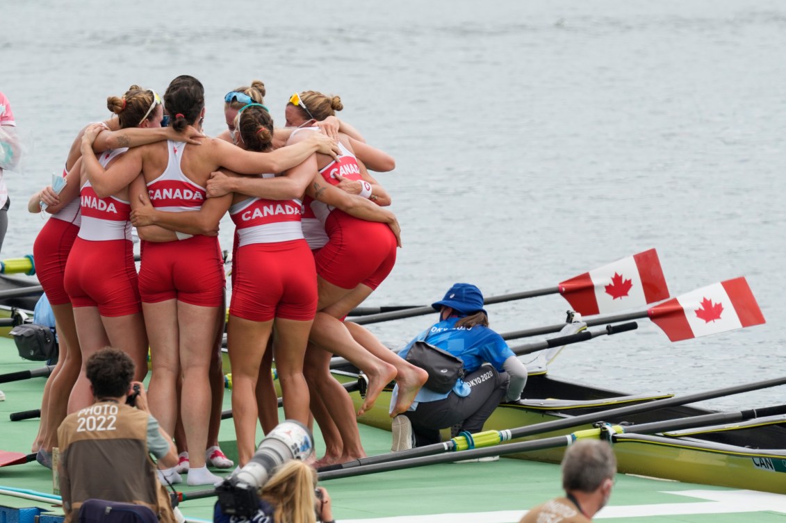 Rowing team hugs in a huddle on the dock 