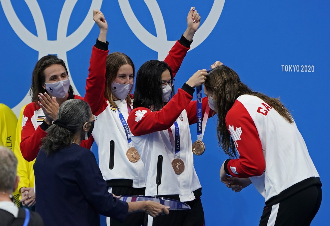 Maggie Mac Neil places medal around Penny Oleksiak's neck