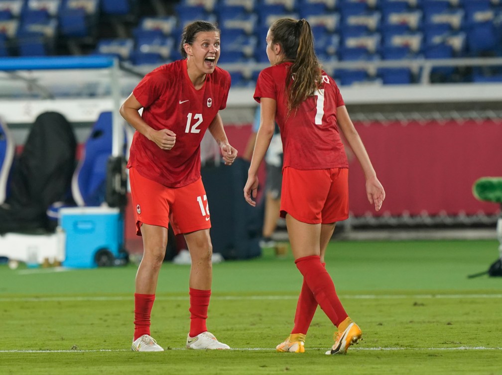 Two soccer players scream at each other in celebration 