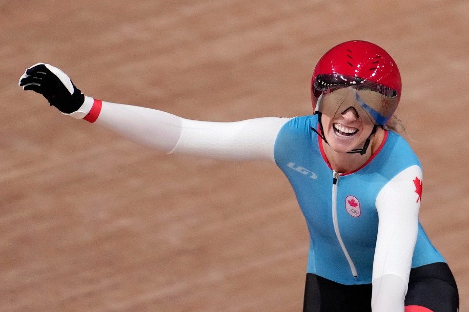 Kelsey Mitchell waves the Canadian flag while doing a victory lap at the velodrome