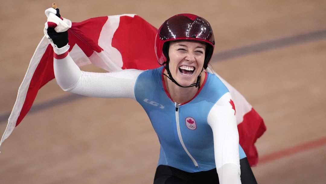Kelsey Mitchell waves the Canadian flag while doing a victory lap at the velodrome