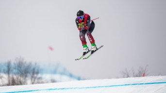 Marielle Thompson flies in the air over a bump on a ski cross course