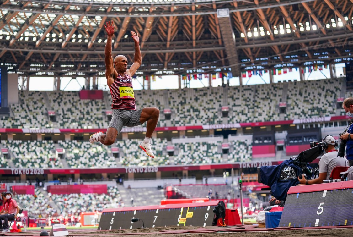 Damian Warner in mid air doing long jump 