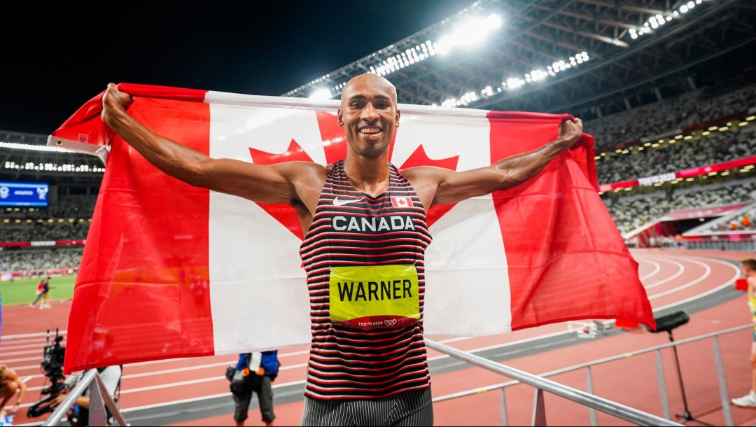 Damian Warner holds the Canadian flag behind him