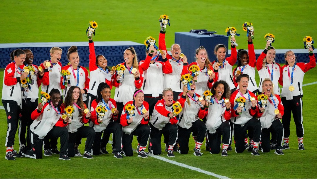 Women's soccer team pose with medals after victory ceremony