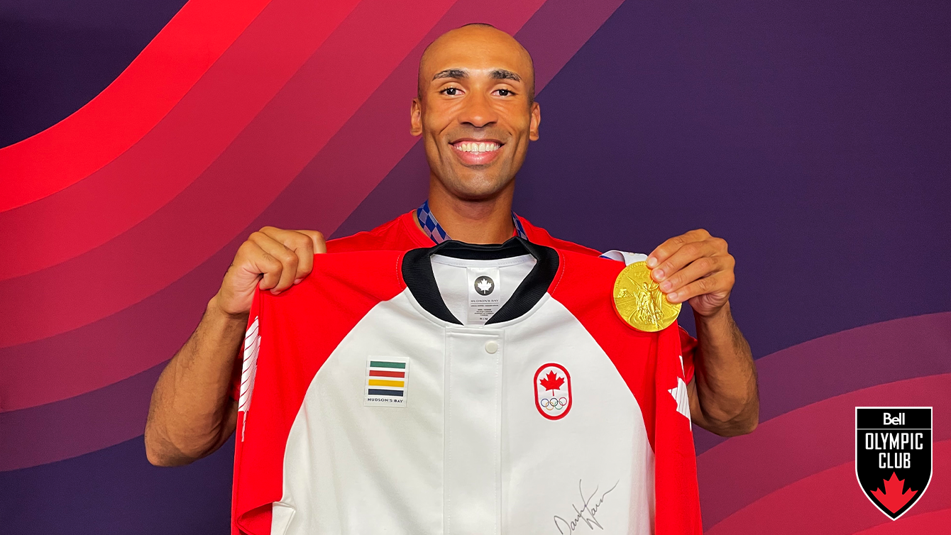 man holding a gold medal and a white jacket with a signature on it