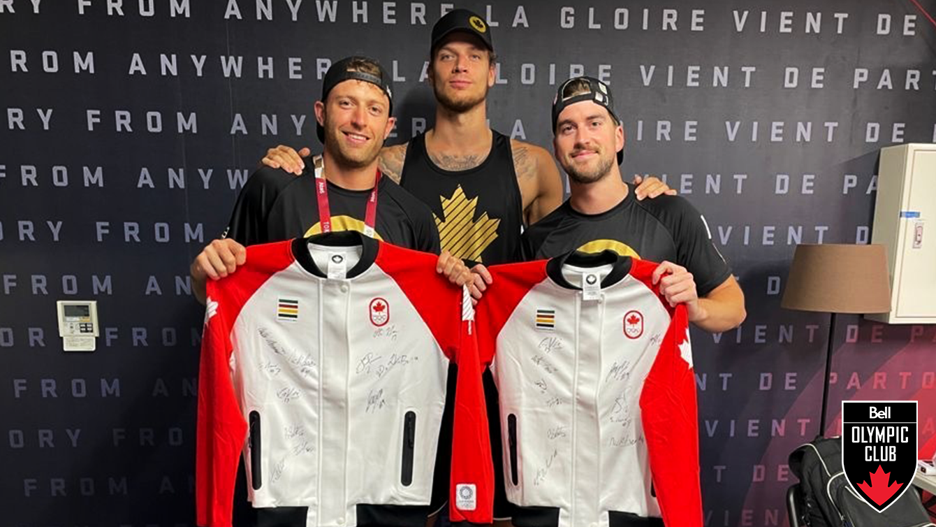 three tall men holding two white team canada jackets with signatures on them