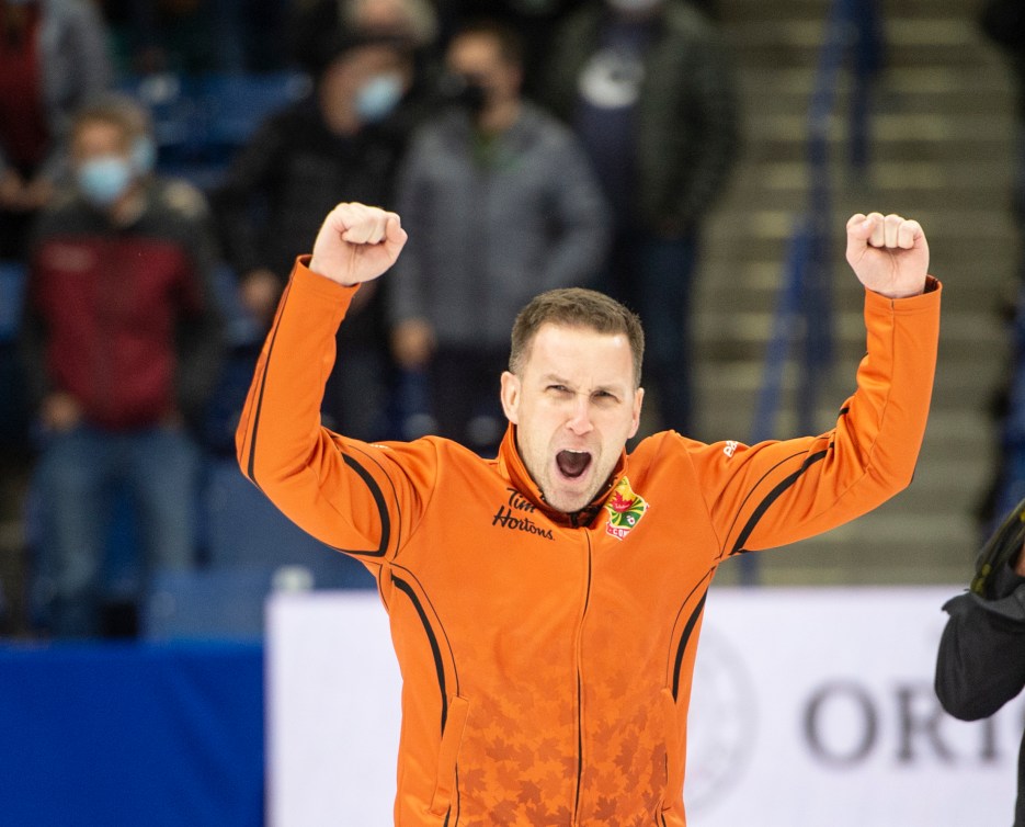 Brad Gushue raises his arms in celebration 