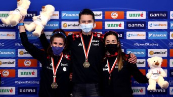 (left to right) Ivanie Blondin, Isabelle Weidemann and Valérie Maltais stand together for a group photo with their gold medals around their neck. They are each holding a white teddy bear.