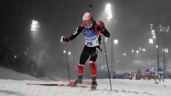 Adam Runnalls skis at night in snowfall in a biathlon race