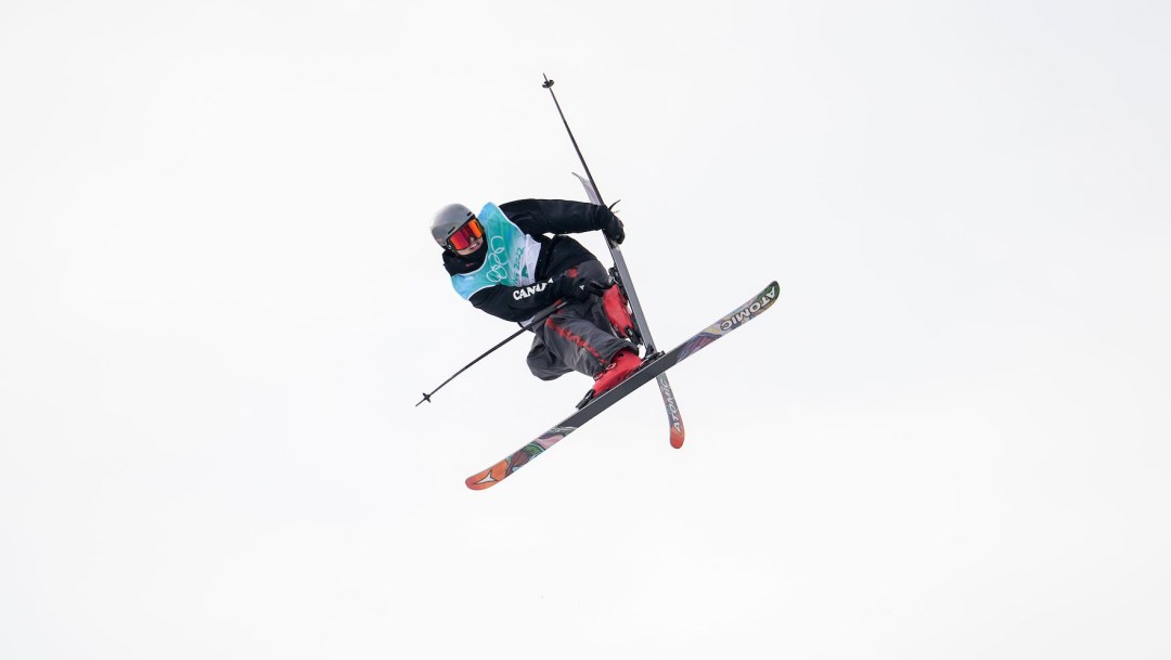 Edouard Therriault grabs his ski while performing a mid air trick