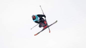Edouard Therriault grabs his ski while performing a mid air trick