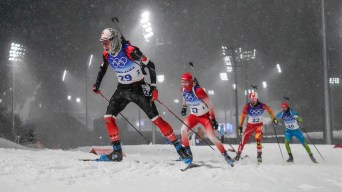 Jules Burnotte skis in snowfall at night in a biathlon race