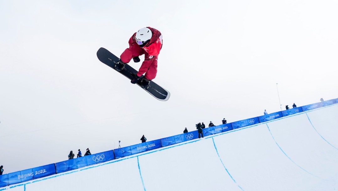 Liam Gill grabs his board doing a trick above the halfpipe