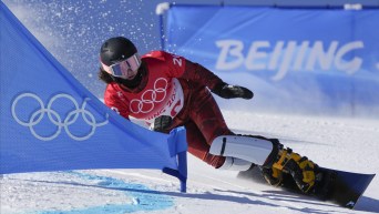 Megan Farrell carves her edge as she snowboards around a gate in a PGS race