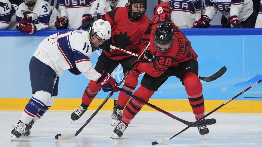 Micah Zandee-Hart battles for the puck against an American player