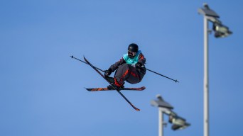 Olivia Asselin grabs her ski while performing a mid air ski trick