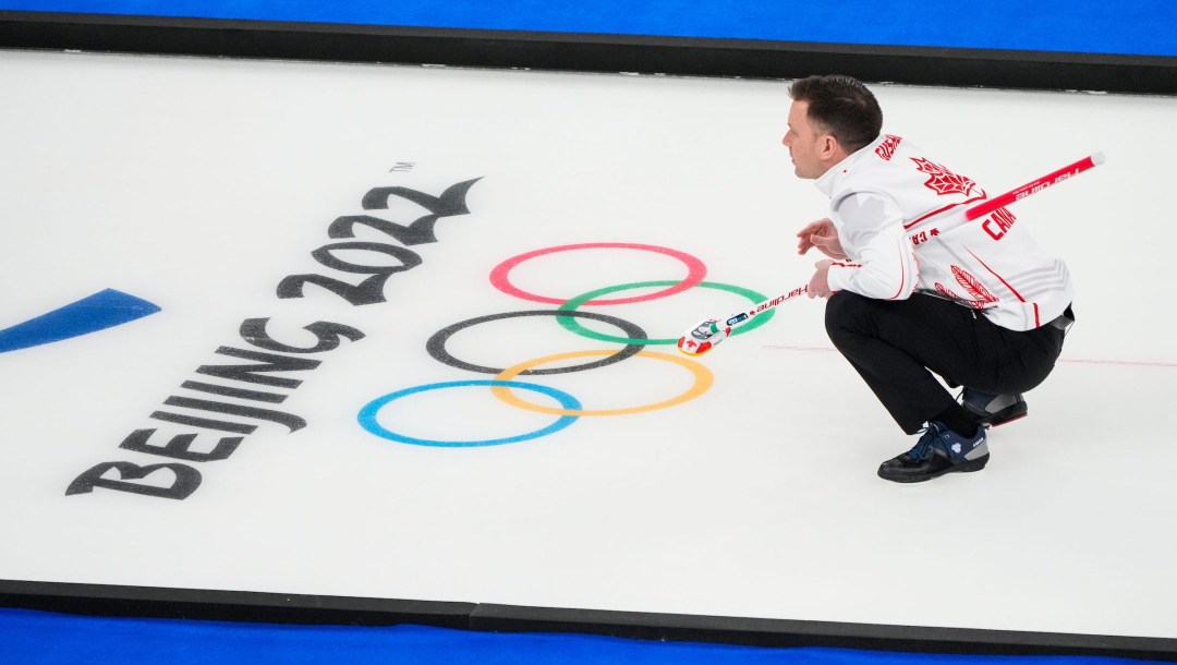 Brad Gushue crouches on the ice to call a shot