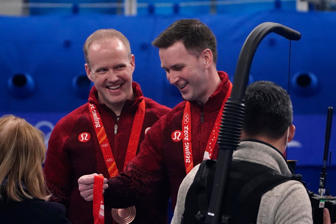 Mark Nichols smiles at Brad Gushue as they receive their medals