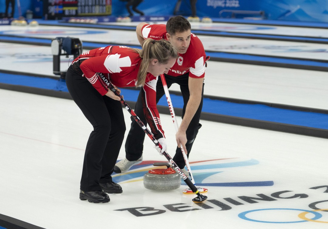 Rachel Homan and John Morris sweep a stone