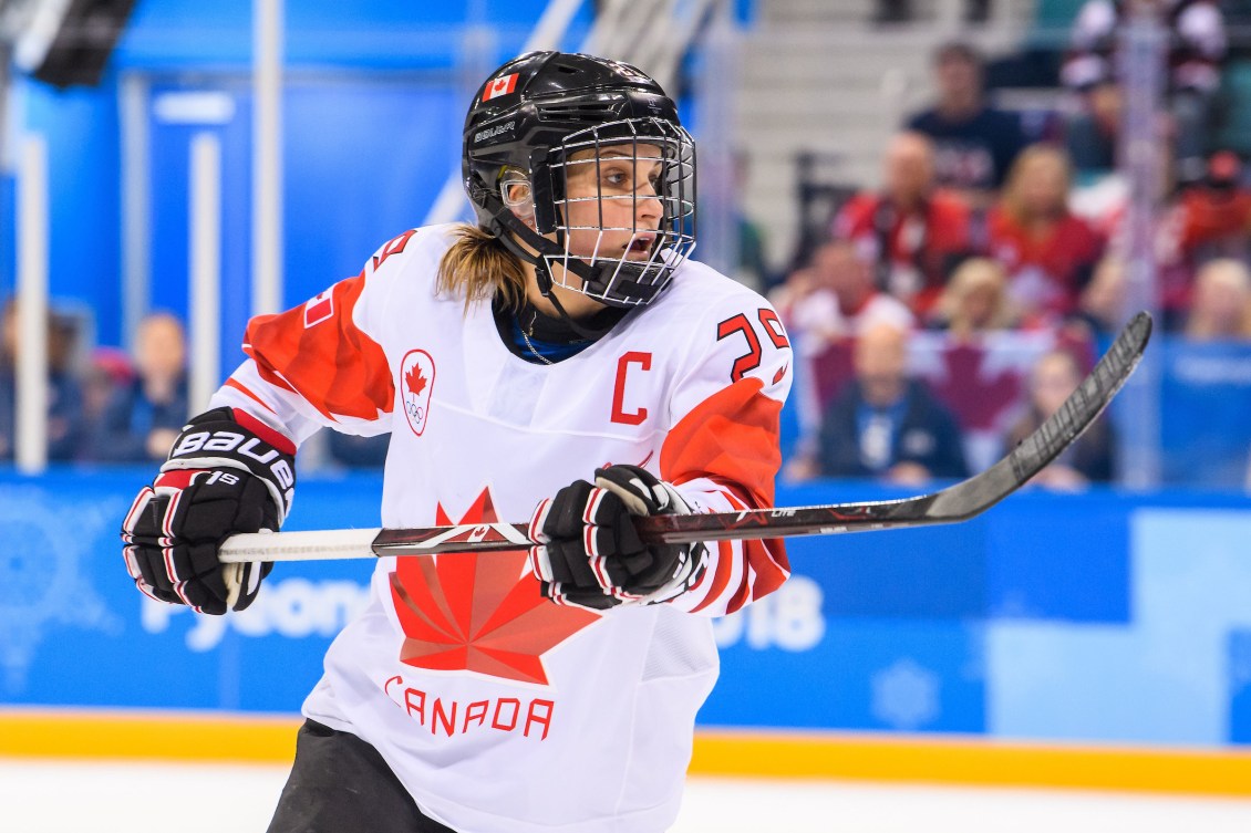 Marie-Philip Poulin lifts her stick to follow the play on the ice