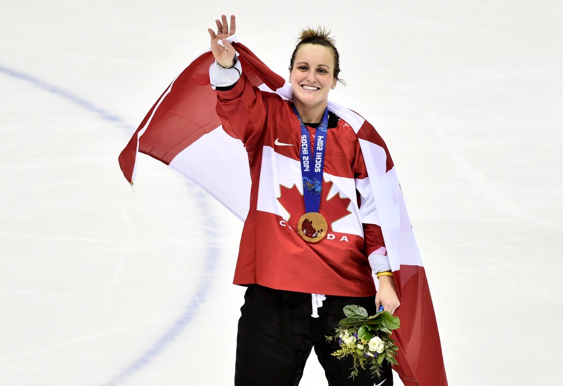 Marie-Philip Poulin waves with the Canadian flag draped over her shoulders