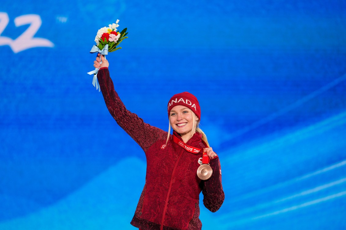 Meryeta O'Dine holds her flowers in the air while wearing her medal