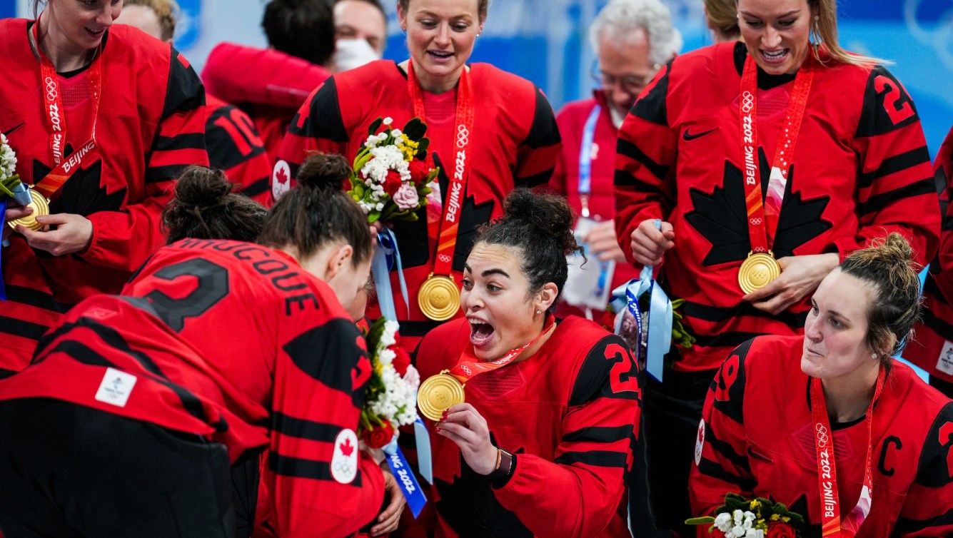 Sarah Nurse shows off her gold medal to teammates with a big grin