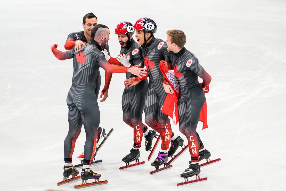 Charles Hamelin goes to hug his four teammates in the short track relay