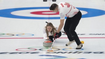 Rachel Homan throws a curling stone while John Morris sweeps