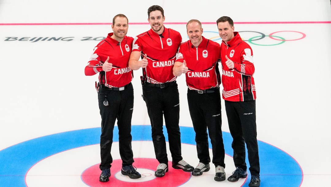 Team Gushue give thumbs up while standing on the rice