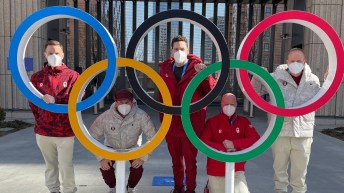 Five people pose inside giant Olympic rings