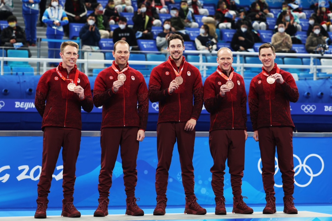 Team Gushue stands on the podium wearing bronze medals