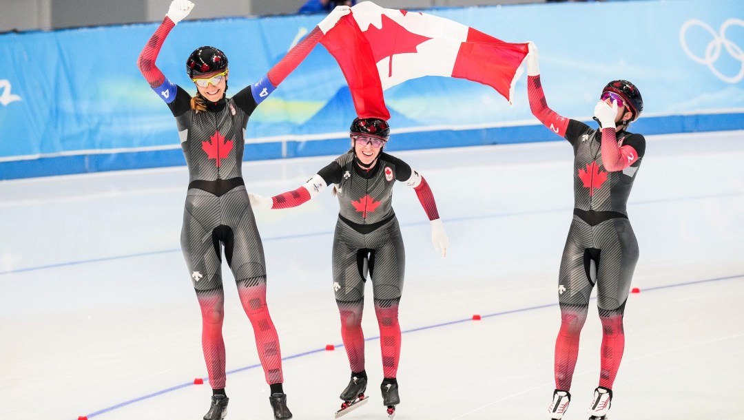 Isabelle Weidemann, Ivanie Blondin and Valerie Maltais carry the Canadian flag on a victory lap at the speed skating oval