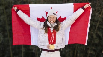 Isabelle Weidemann poses with the Canadian flag while wearing her three Olympic medals