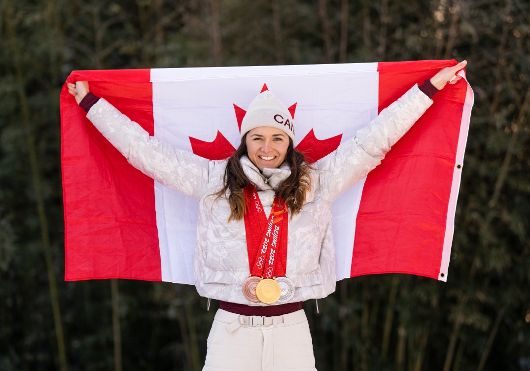 Isabelle Weidemann poses with the Canadian flag while wearing her three Olympic medals 