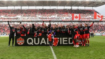 Canadian men's soccer team stands behind a sign that says qualified