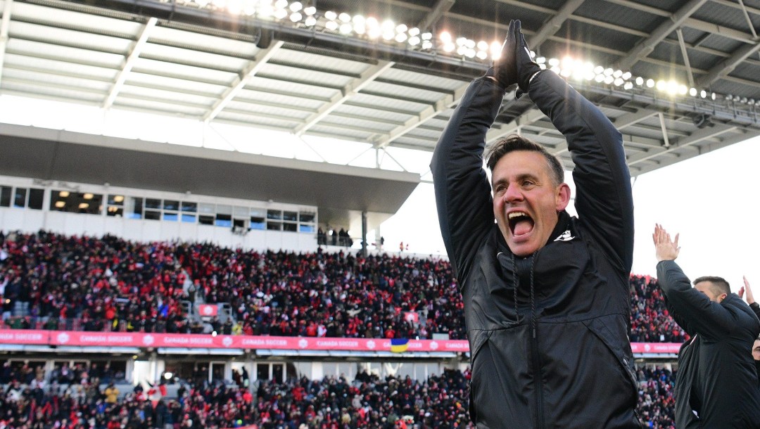 John Herdman claps his hands over his head in celebration