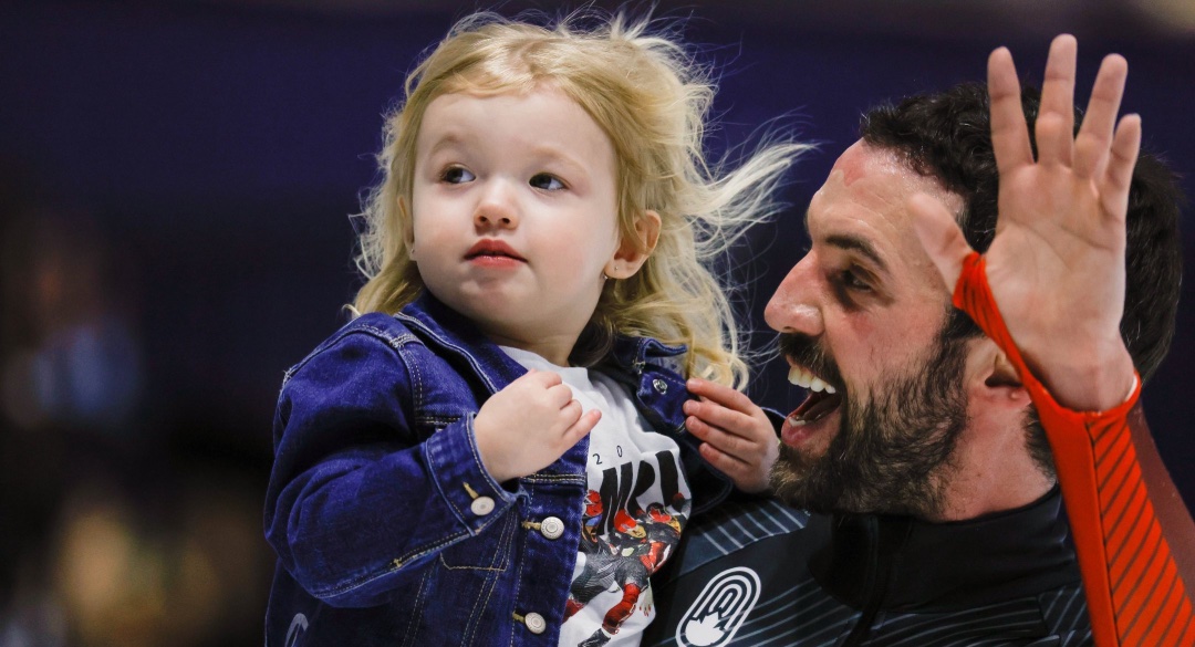 a man holds his daughter and waves