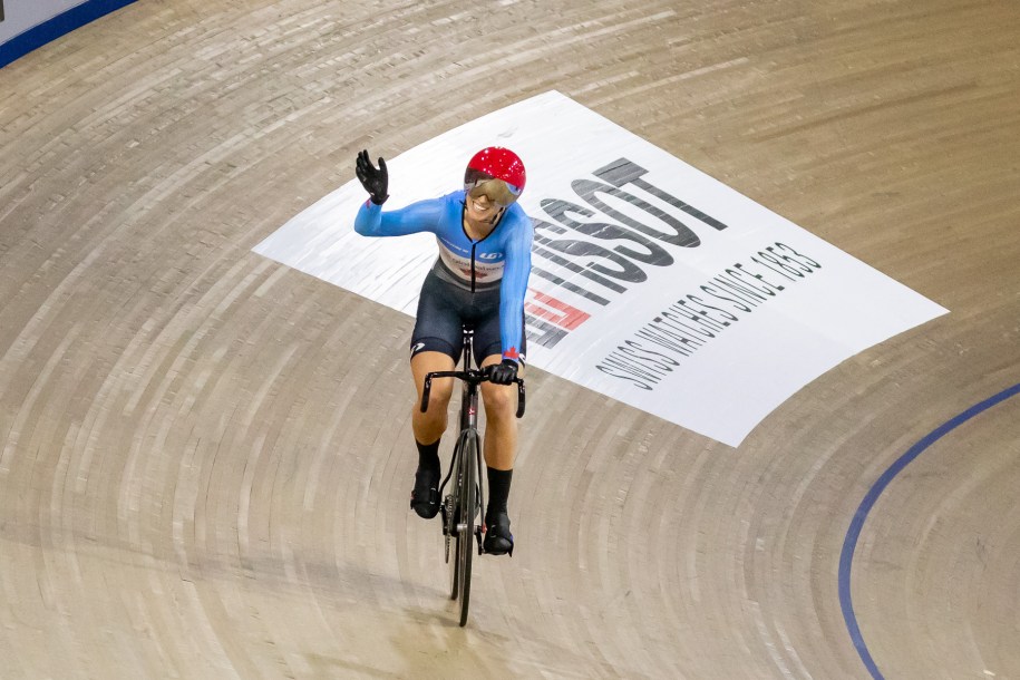 Kelsey Mitchell waves to the crowd while riding her bike